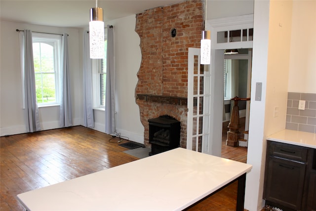 kitchen featuring light wood-type flooring, pendant lighting, dark brown cabinets, a fireplace, and backsplash