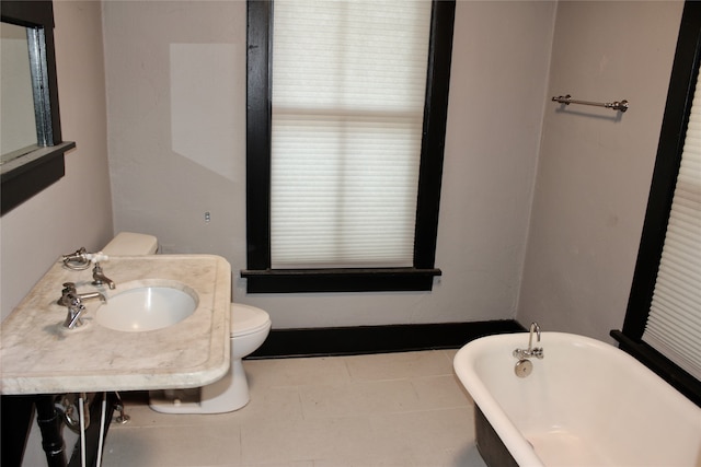 bathroom featuring sink, toilet, a bath, and tile patterned floors