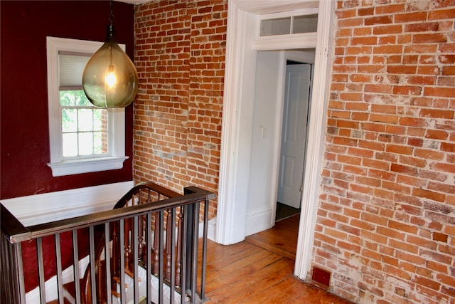 hall featuring brick wall and light wood-type flooring