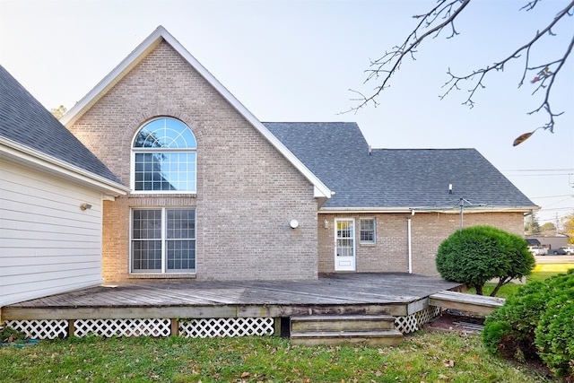 back of property featuring a wooden deck and a yard