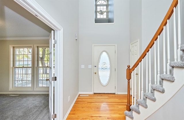 foyer entrance with light wood-type flooring and crown molding