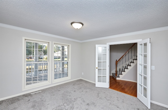 carpeted spare room featuring ornamental molding, french doors, and a textured ceiling