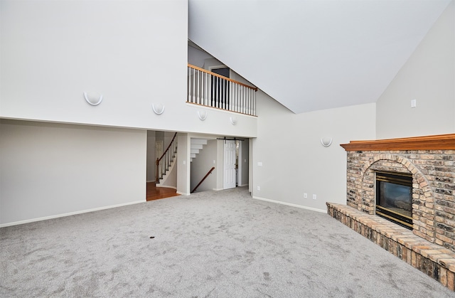 unfurnished living room featuring a brick fireplace, high vaulted ceiling, and carpet flooring