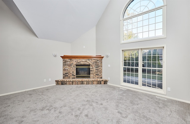 unfurnished living room featuring a brick fireplace, high vaulted ceiling, carpet flooring, and a wealth of natural light