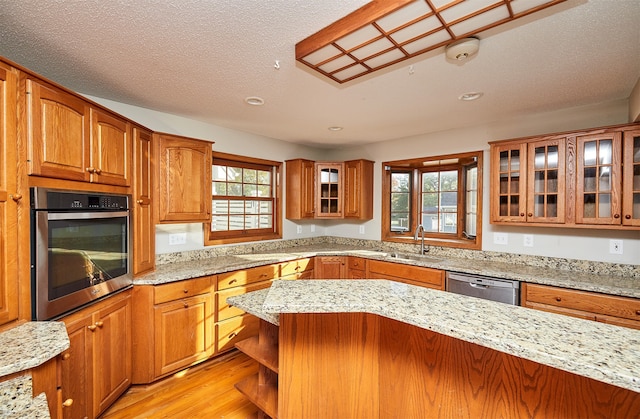 kitchen featuring light stone counters, light wood-type flooring, stainless steel appliances, and plenty of natural light