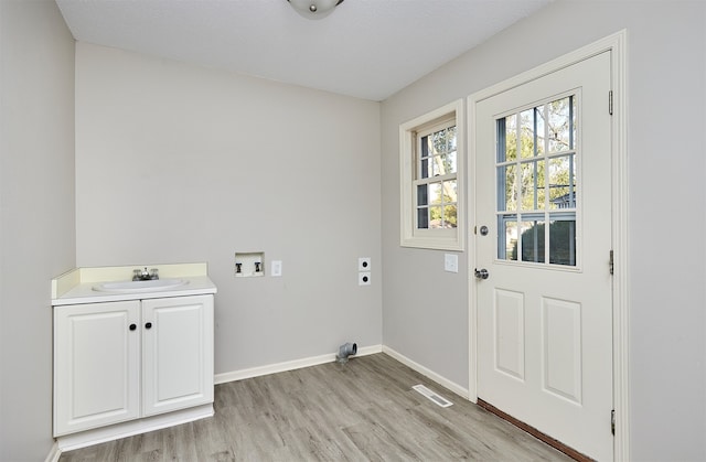 washroom featuring hookup for a washing machine, sink, light hardwood / wood-style flooring, electric dryer hookup, and cabinets