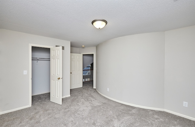 unfurnished bedroom with light carpet, a textured ceiling, and a closet