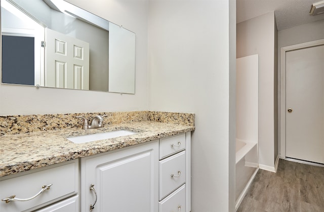 bathroom featuring a bathtub, hardwood / wood-style flooring, vanity, and a textured ceiling