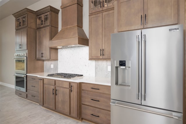 kitchen featuring decorative backsplash, appliances with stainless steel finishes, and premium range hood