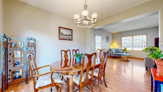 dining space with light wood-type flooring and a notable chandelier