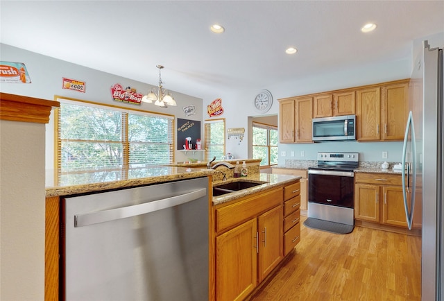 kitchen featuring light wood-type flooring, stainless steel appliances, sink, a notable chandelier, and hanging light fixtures