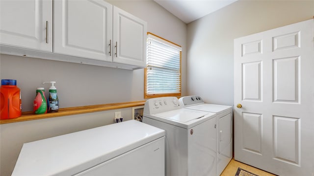 laundry area with washer and dryer, light tile patterned floors, and cabinets