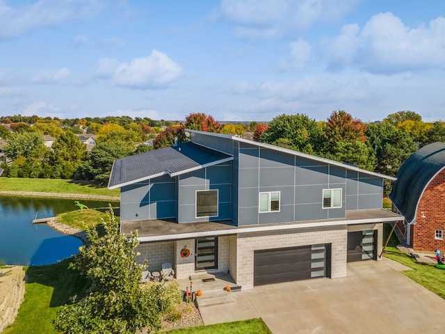 contemporary home featuring a water view, a garage, and a front lawn