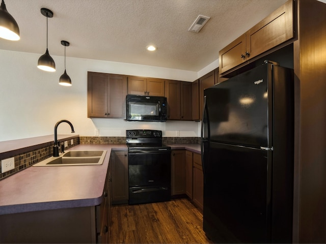 kitchen with pendant lighting, dark wood-type flooring, sink, backsplash, and black appliances