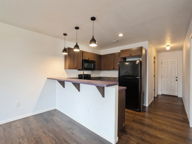 kitchen with a kitchen breakfast bar, hanging light fixtures, kitchen peninsula, and black appliances