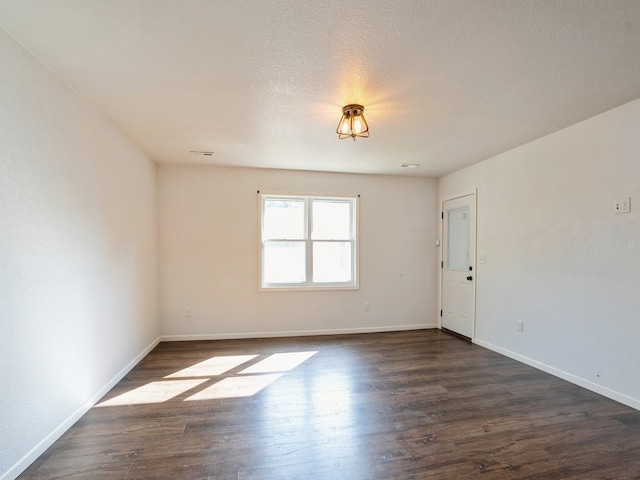 spare room featuring a textured ceiling and dark hardwood / wood-style floors