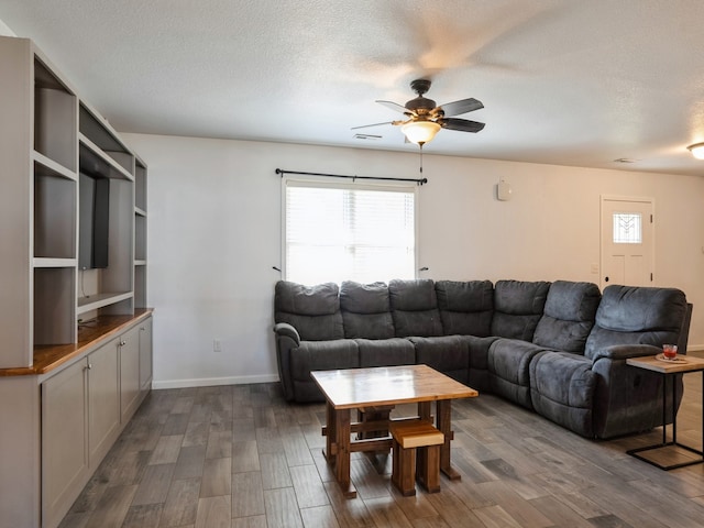 living room with ceiling fan, a textured ceiling, and dark hardwood / wood-style floors