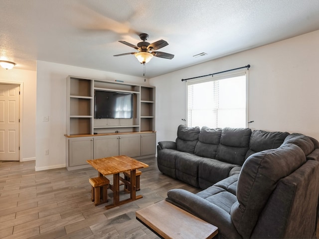 living room featuring a textured ceiling, ceiling fan, and light hardwood / wood-style flooring