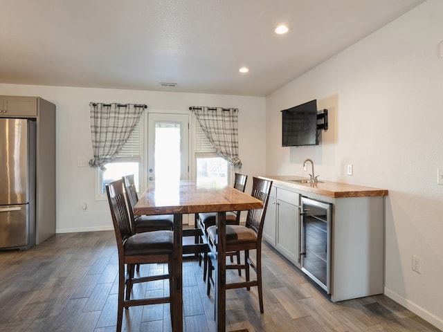 dining room with wood-type flooring, wine cooler, and sink