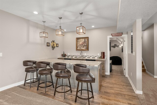 bar featuring a textured ceiling, decorative light fixtures, and sink