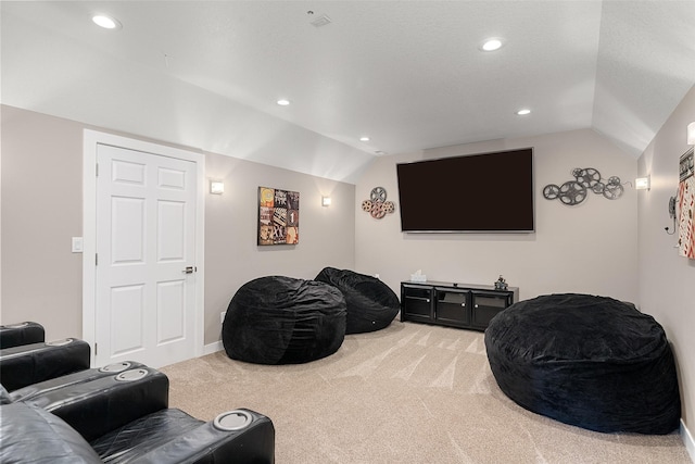 home theater room with light carpet and vaulted ceiling