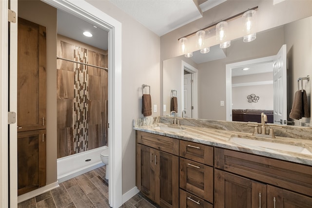 bathroom featuring a tile shower, vanity, and toilet