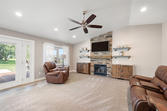 carpeted living room with vaulted ceiling, ceiling fan, and a stone fireplace