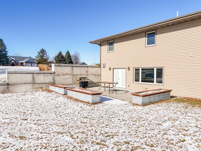 snow covered rear of property with a patio