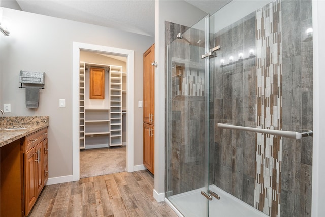 bathroom featuring hardwood / wood-style flooring, vanity, an enclosed shower, and a textured ceiling