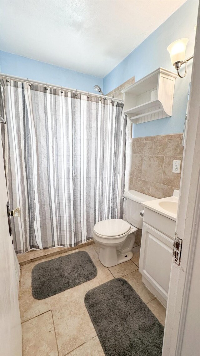 bathroom with tile patterned floors, toilet, vanity, tile walls, and a shower with shower curtain