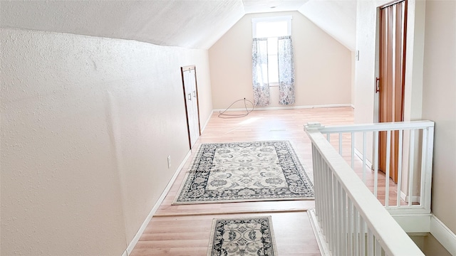 hall with hardwood / wood-style floors and vaulted ceiling