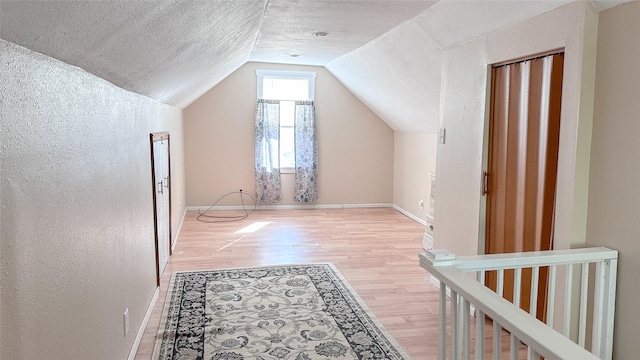 bonus room with hardwood / wood-style floors, a textured ceiling, and vaulted ceiling