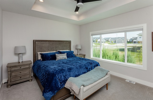 carpeted bedroom featuring ceiling fan and a tray ceiling