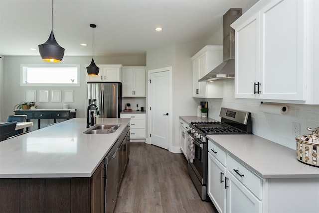 kitchen featuring stainless steel appliances, white cabinets, wall chimney exhaust hood, sink, and light hardwood / wood-style flooring