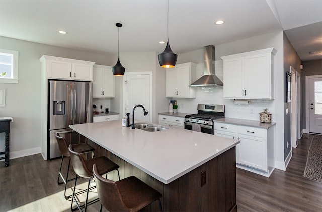 kitchen with wall chimney range hood, white cabinetry, sink, and stainless steel appliances