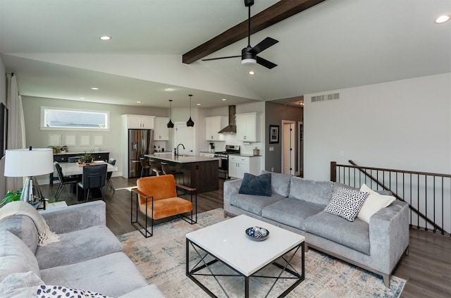 living room with sink, vaulted ceiling with beams, light wood-type flooring, and ceiling fan