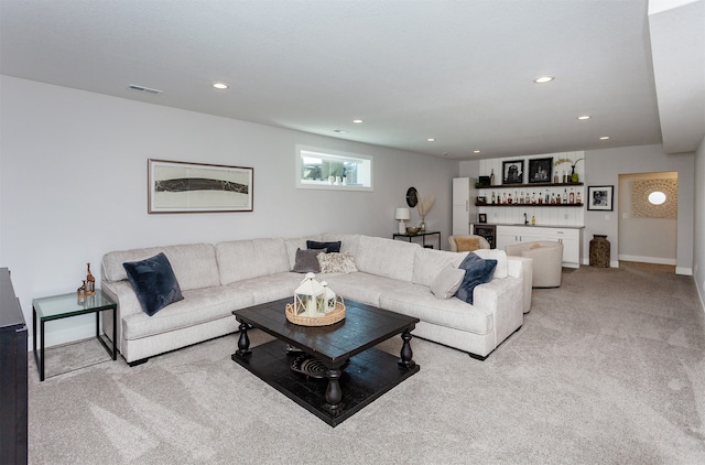 carpeted living room featuring wine cooler and bar