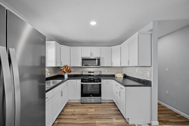 kitchen featuring light hardwood / wood-style floors, sink, stainless steel appliances, backsplash, and white cabinets