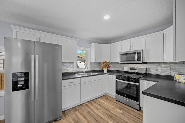 kitchen with appliances with stainless steel finishes, white cabinetry, and sink