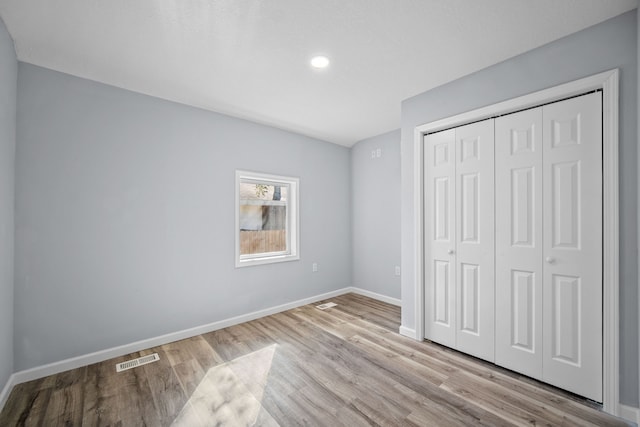 unfurnished bedroom featuring light wood-type flooring and a closet