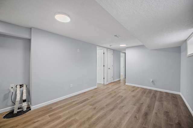 basement featuring light hardwood / wood-style flooring and a textured ceiling