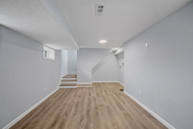 basement featuring a textured ceiling and light wood-type flooring