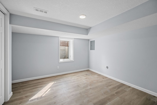 empty room featuring electric panel, hardwood / wood-style floors, and a textured ceiling