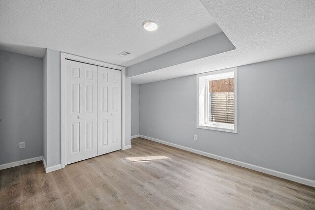 unfurnished bedroom featuring a closet, light hardwood / wood-style floors, and a textured ceiling