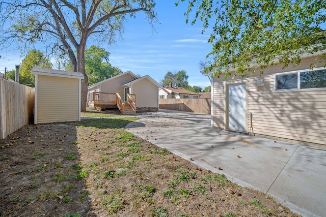 view of yard with a storage unit, a deck, and a patio area