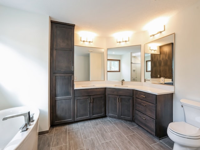 bathroom featuring vanity, a tub to relax in, toilet, and a textured ceiling