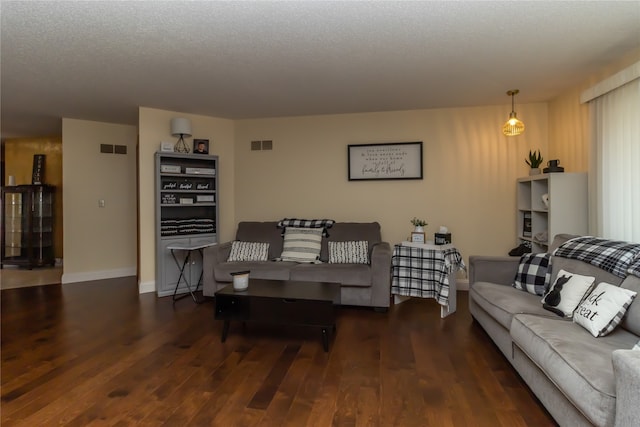 living room with a textured ceiling and dark hardwood / wood-style floors