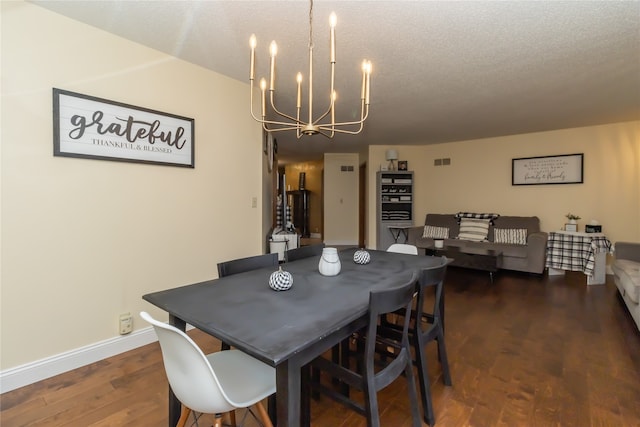 dining room with an inviting chandelier, a textured ceiling, and dark wood-type flooring