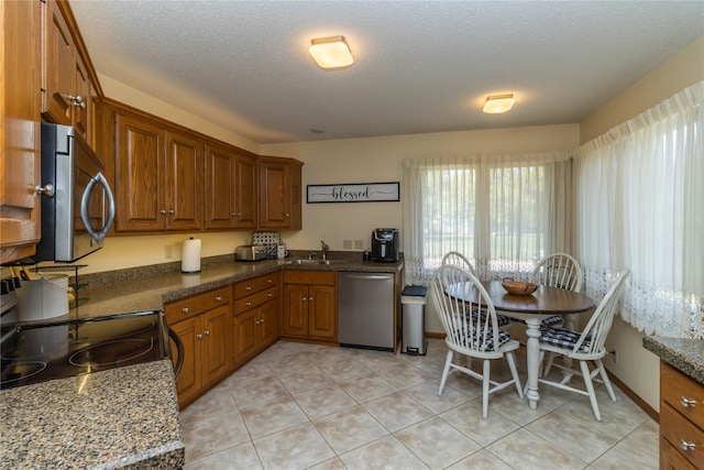 kitchen with stainless steel appliances, sink, light tile patterned floors, and a textured ceiling