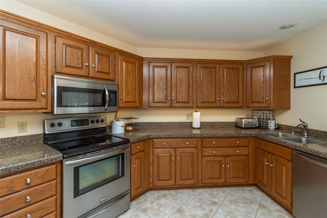 kitchen with stainless steel appliances, sink, light tile patterned floors, and a textured ceiling